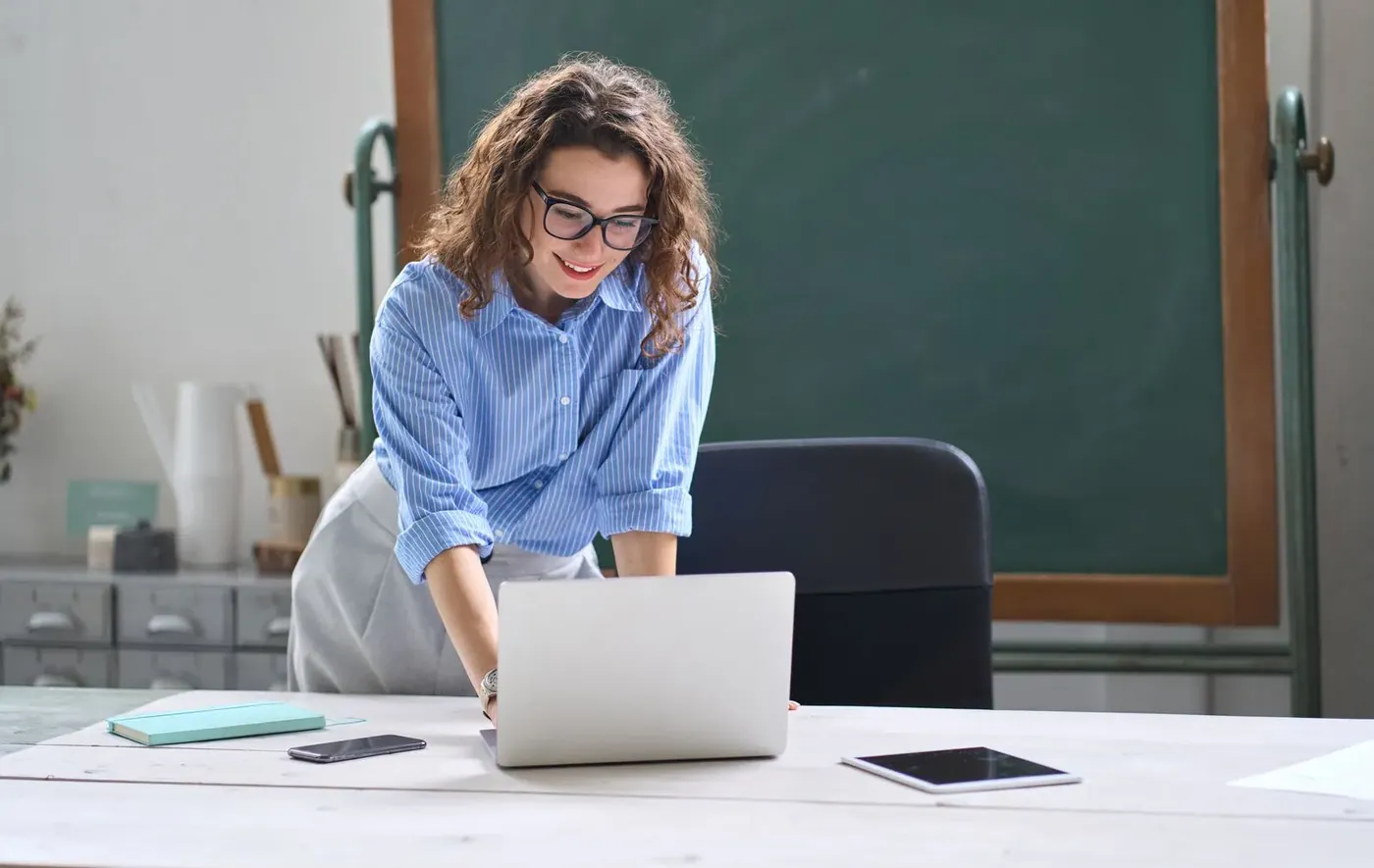 A school leader smiling as she works on a laptop